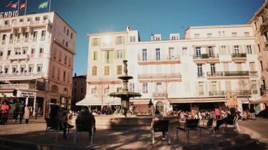 Cannes, Fransa - 23 Aralık 2025: İnsanlar canlı bir meydanda bir çeşmenin etrafında oturup dinleniyorlar