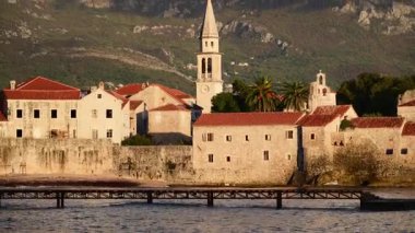 Adriyatik Denizi kıyısında kırmızı çatıları ve çan kulesi olan Budva Eski Şehir binaları