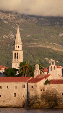 Budva Eski Kasabası tarihi binalar, kilise kuleleri ve dağlara ve Adriyatik Denizi 'ne karşı palmiye ağaçlarını gösteriyor