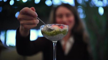 Taze meyve soslu chia pudingi yiyen kadın