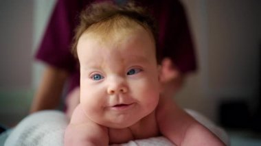 Karnının üzerine uzanmış bir bebeğin karnını kapatırken bir yetişkin tarafından nazikçe destekleniyor.