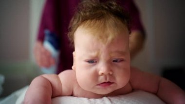 Karnının üzerine uzanmış bir bebeğin karnını kapatırken bir yetişkin tarafından nazikçe destekleniyor.