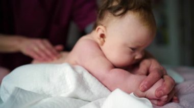 Karın yastığında dinlenen bir bebeğin yan görüntüsü. Bakıcının elleri destek için yakınlarda dururken.