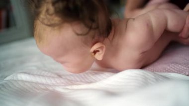 Bebek sırt üstü yatarken bir yetişkin onlara masaj yapıyor ve hareket egzersizleri yapıyor.