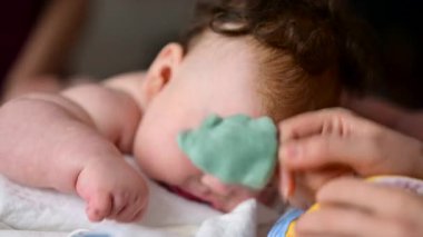 Cute baby lying on stomach during tummy time while interacting with a pacifier
