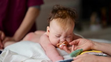 Bebek karnının üstünde yatarken emzik ile etkileşime giriyor.