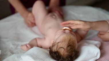 Bebek bakıcısı bebeğe masaj yaparken yumuşak bir yatakta uzanan bir bebek.
