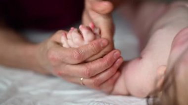 Yetişkinlerin ellerine yaklaş. Bebeğin koluna ve avucuna nazikçe masaj yap.