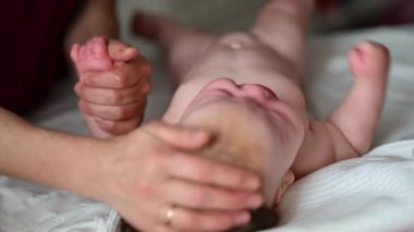 Yetişkinlerin ellerine yaklaş. Bebeğin koluna ve avucuna nazikçe masaj yap.