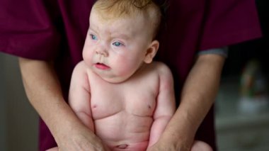 Bebek dik otururken bir bakıcı tarafından destekleniyor.