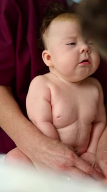 Bakıcının kucağında rutin bir bakım sırasında dinlenen bebek. Dikey