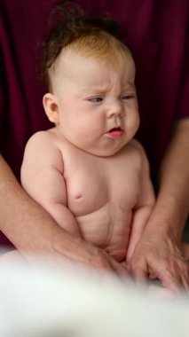 Bakıcının kucağında rutin bir bakım sırasında dinlenen bebek. Dikey