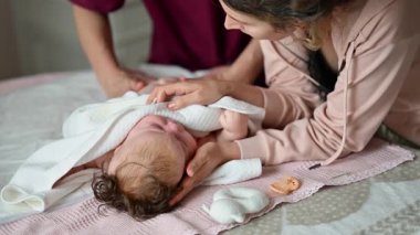 Anne bebeğinin üzerine eğilirken bir yatakta bakım sırasında asistanlık yapıyor.