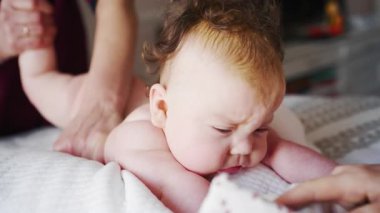 Close up of a baby while an adult gently supports them during a home care routine