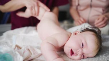 Bebek yetişkinler tarafından karın çalışması ve hareket egzersizleri yaparken destekleniyor.