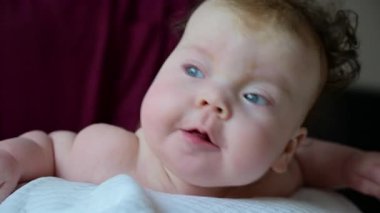 Bebek bakıcısı nazikçe desteklerken karın boşluğunda başını kaldıran bebek.