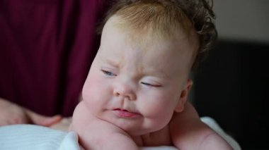 Bebek bakıcısı nazikçe desteklerken karın boşluğunda başını kaldıran bebek.