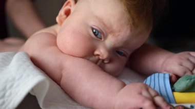 Bebek masaj sırasında renkli yumuşak oyuncaklara odaklanıyor