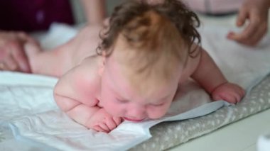 Bebek karnının üstünde yatarken bir yetişkin onlara masaj yapıyor ve hareket egzersizleri yapıyor.