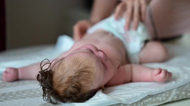 Anne altlarına bez bağlarken bebek sırt üstü yatar.
