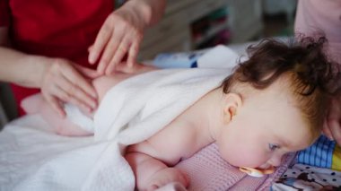 Karnında battaniyeyle sırt üstü uzanmış, emzik ağızda ve yanında bakıcı olan bebeğe yakın dur.