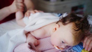 Bebek karnının üstünde yatarken bir yetişkin onlara masaj yapıyor ve hareket egzersizleri yapıyor.
