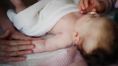 Bebek sakince dinlenirken bebeğin kollarına ve göğüs bölgesine hafifçe masaj yapan bakıcıya yaklaş.