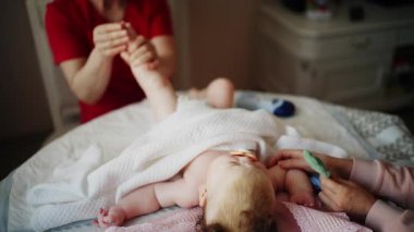 Bebek emzik ile sırtında bebek bakıcısı bebeğin ayaklarına nazikçe masaj yapar.