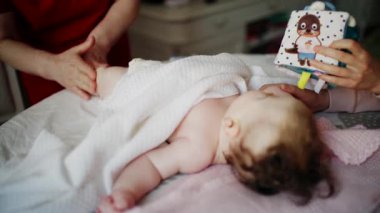 Bebek masaj sırasında renkli yumuşak oyuncaklara odaklanıyor