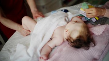 Bebek masaj sırasında renkli yumuşak oyuncaklara odaklanıyor