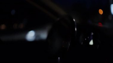 Gece bir araba gösterge paneli ve enstrüman kümesinin yakın görüntüsü, kısmen direksiyon simidinden görülüyor.