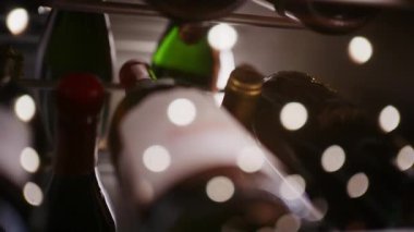 Sıcak ışıklandırma ve sığ alan derinliği ile yatay olarak bir rafta depolanmış şarap şişeleri aşırı yakın