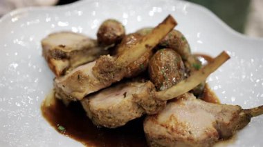 Kızarmış patates ve sosla servis edilen kuzu pirzolası.