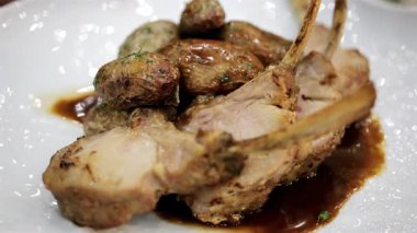 Kızarmış patates ve sosla servis edilen kuzu pirzolası.