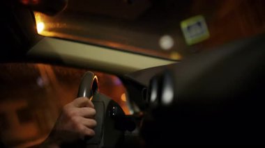 Gece bir arabanın içinde direksiyon tutan bir sürücünün elini kapat.