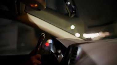 Gece bir arabanın içinde direksiyon tutan bir sürücünün elini kapat.