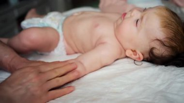 Yetişkinlerin ellerine yaklaş. Bebeğin koluna ve avucuna nazikçe masaj yap.