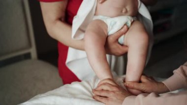 Bakıcı bebekle hareket egzersizi yapıyor.