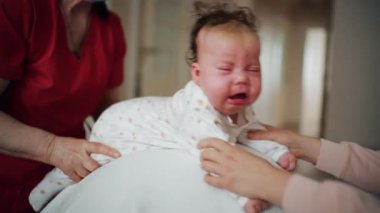 Yetişkinler bebeğin gövdesini ve omuzlarını desteklerken bebek de dengeli bir topun üzerine yerleştirilir.