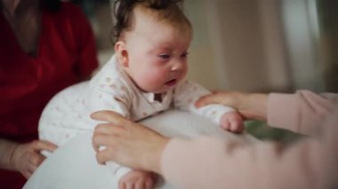 Yetişkinler bebeğin gövdesini ve omuzlarını desteklerken bebek de dengeli bir topun üzerine yerleştirilir.