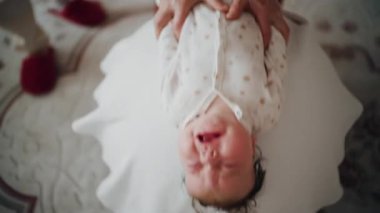 Yetişkinler bebeğin gövdesini ve omuzlarını desteklerken bebek dengeli bir topun üzerine yerleştirildi.