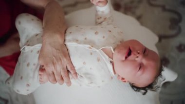 Yetişkinler bebeğin gövdesini ve omuzlarını desteklerken bebek dengeli bir topun üzerine yerleştirildi.