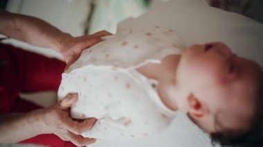 Yetişkinler bebeğin gövdesini ve omuzlarını desteklerken bebek dengeli bir topun üzerine yerleştirildi.