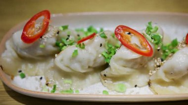 Kırmızı biberli ve yeşil soğanlı tavada kızartılmış hamur köfteleri seramik tabakta.