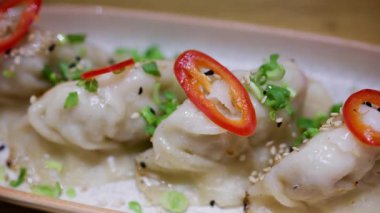 Kırmızı biberli ve yeşil soğanlı tavada kızartılmış hamur köfteleri seramik tabakta.