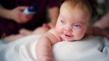 Bebek karnının üstünde yatarken bir yetişkin onlara masaj yapıyor ve hareket egzersizleri yapıyor.