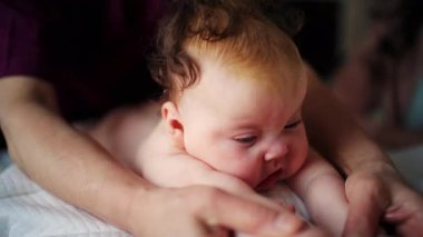 Baby lying on their tummy while an adult massages them and performs mobility exercises