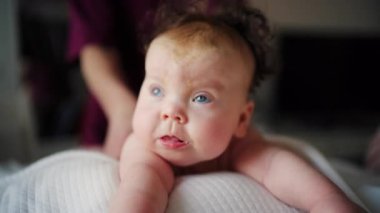 Bebek karnının üstünde yatarken bir yetişkin onlara masaj yapıyor ve hareket egzersizleri yapıyor.