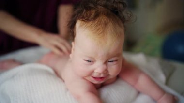 Baby lying on their tummy while an adult massages them and performs mobility exercises