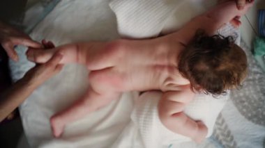 Bebek karnının üstünde yatarken bir yetişkin onlara masaj yapıyor ve hareket egzersizleri yapıyor.